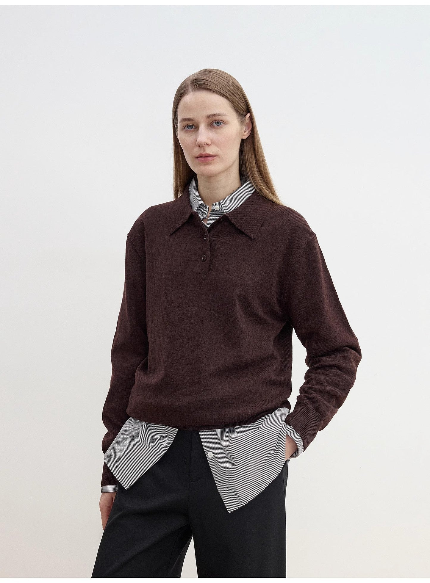 Woman wearing a brown sweater over a gray shirt with a white background
