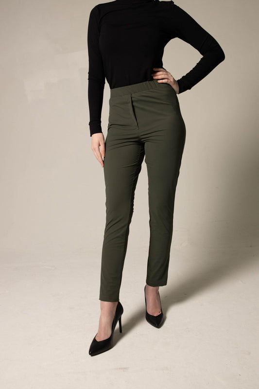 Person wearing a simple black top and loose green pants against a beige background. This stylish lesbian outfit is a sharp example of confident lesbian fashion and authentic lesbian style.