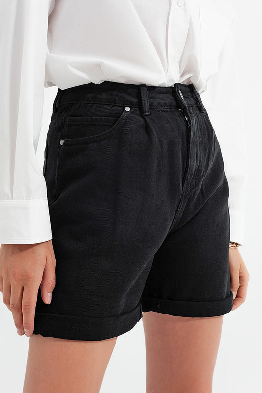 Person wearing classic black shorts and a simple white shirt against a light gray background. This comfortable lesbian outfit is a perfect example of casual lesbian fashion and authentic lesbian style.