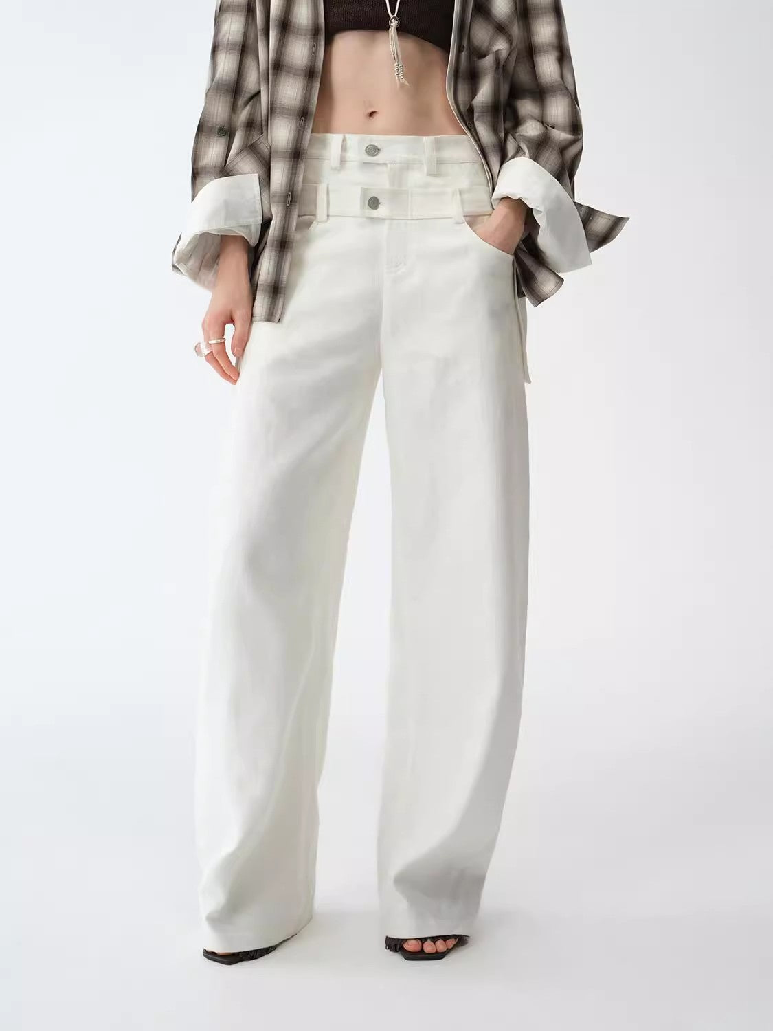 Person wearing white wide-leg pants with a plaid shirt on a white background. This casual lesbian outfit is a perfect example of confident lesbian fashion style and effortless lesbian style.