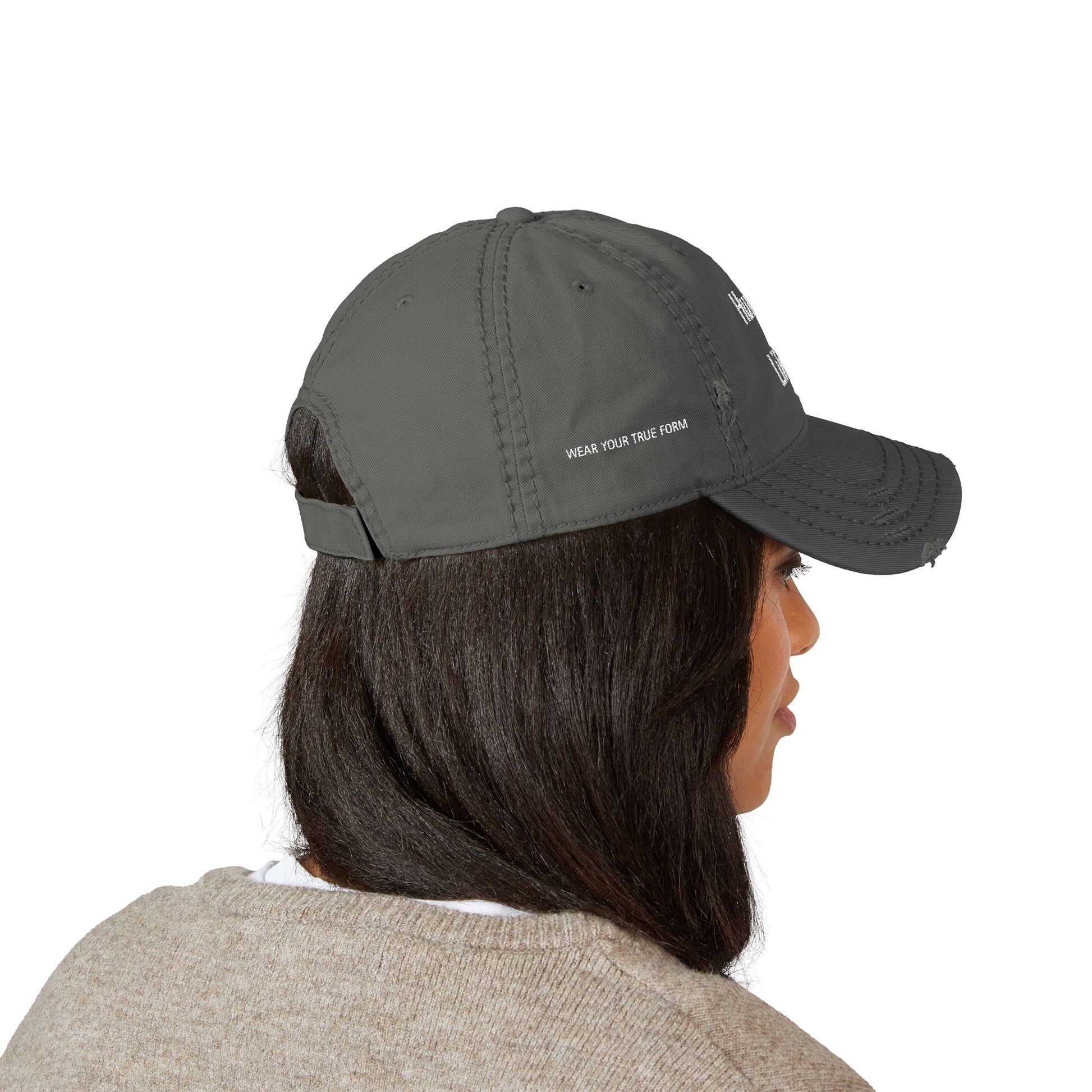 Person wearing a stylish gray cap with text/logo embroidered on the front against a white background. This headwear is an essential accessory for defining authentic lesbian style and confident lesbian fashion.