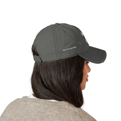 Person wearing a stylish gray cap with text/logo embroidered on the front against a white background. This headwear is an essential accessory for defining authentic lesbian style and confident lesbian fashion.