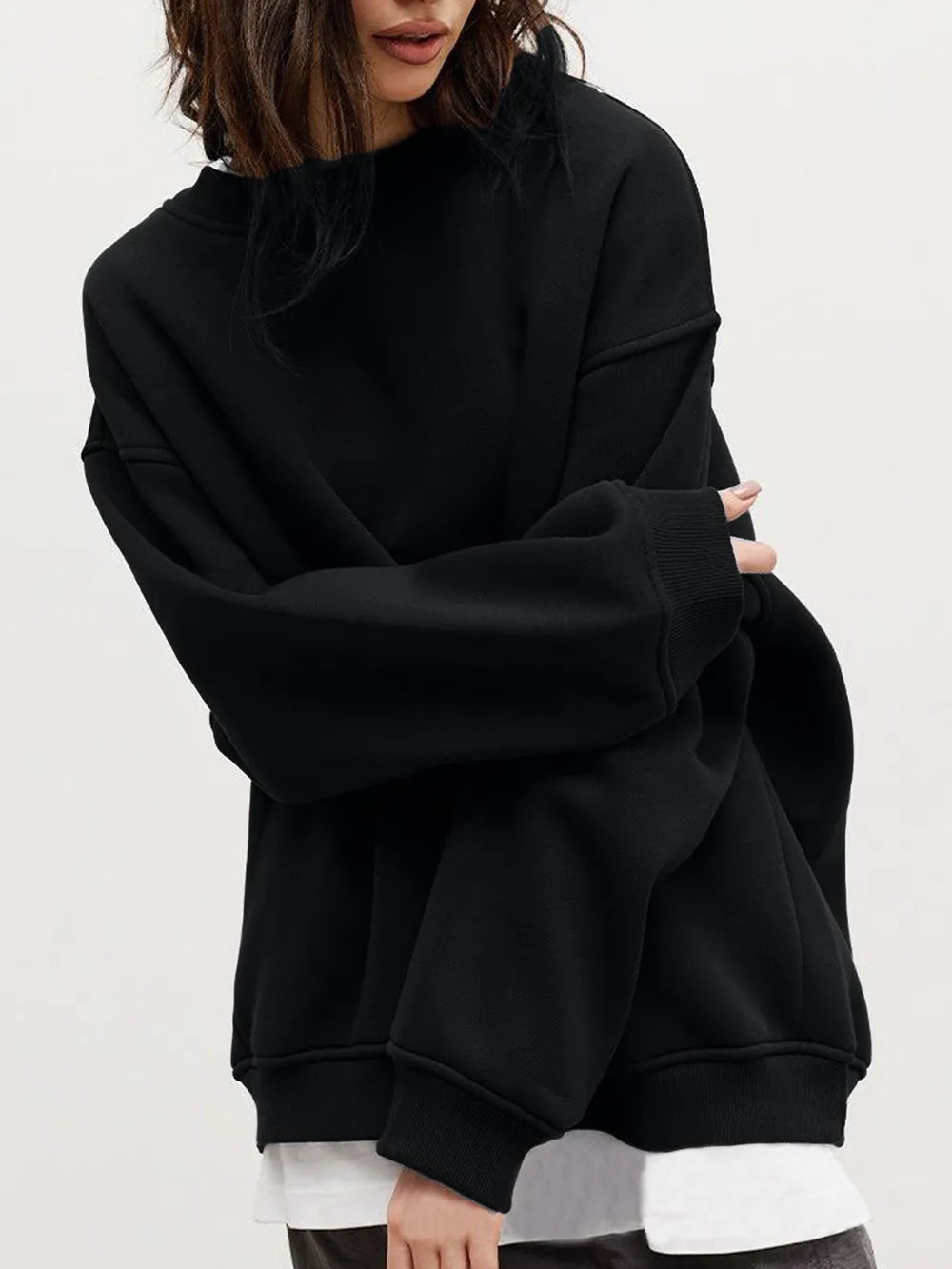 Person wearing a comfortable black oversized sweatshirt with a crisp white shirt underneath on a plain background. This classic lesbian outfit is a perfect example of casual lesbian fashion and authentic lesbian style.