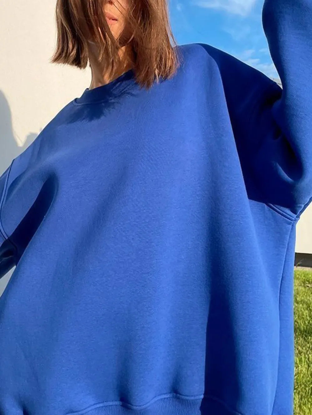 Person wearing a comfortable blue oversized sweatshirt on a light gray background. This classic lesbian outfit is a perfect example of casual lesbian clothing and relaxed lesbian style.