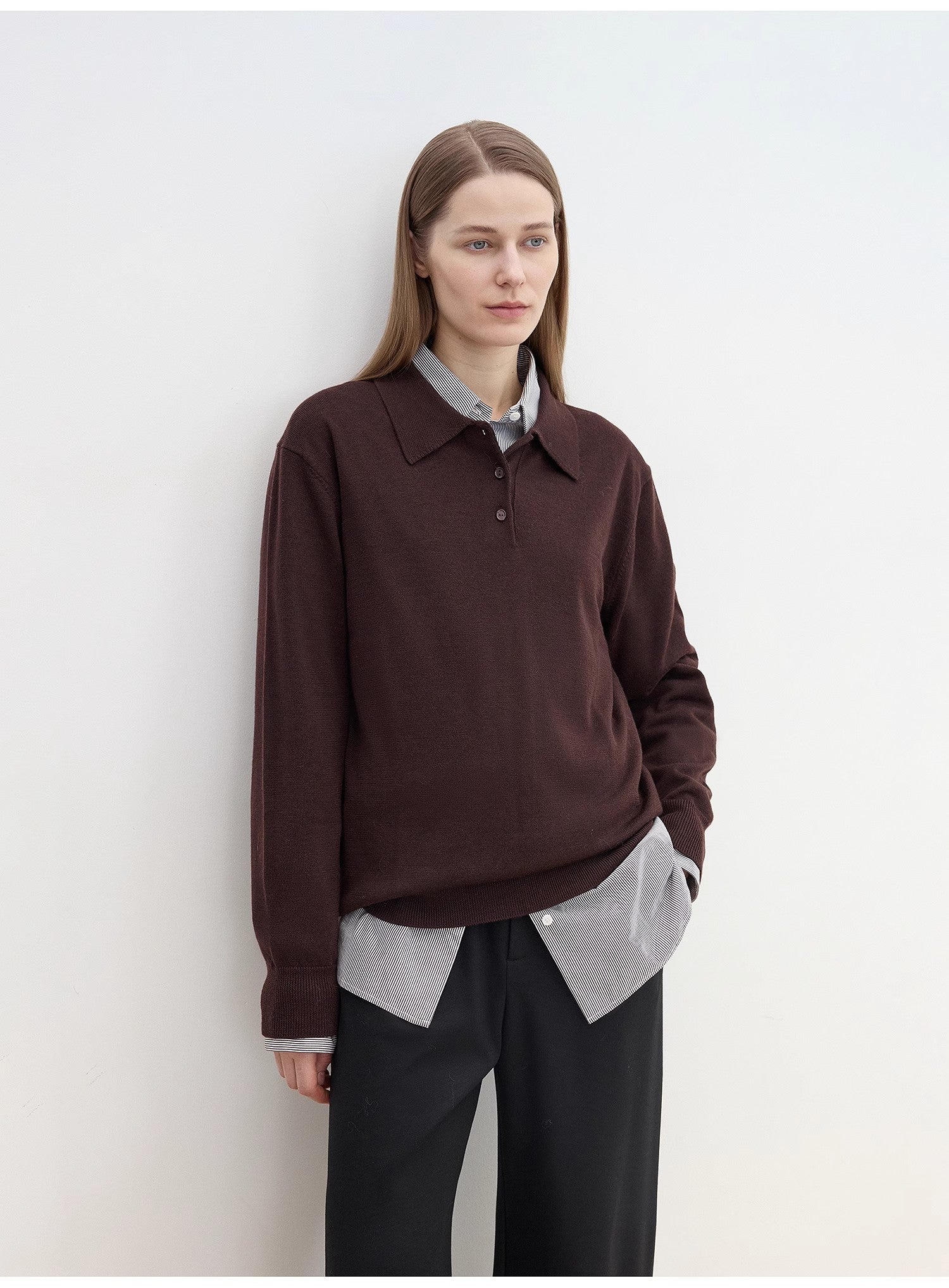 Person wearing a cozy brown sweater over a light shirt with sharp black pants against a white background. This classic lesbian outfit is a perfect example of confident lesbian fashion and authentic lesbian style.