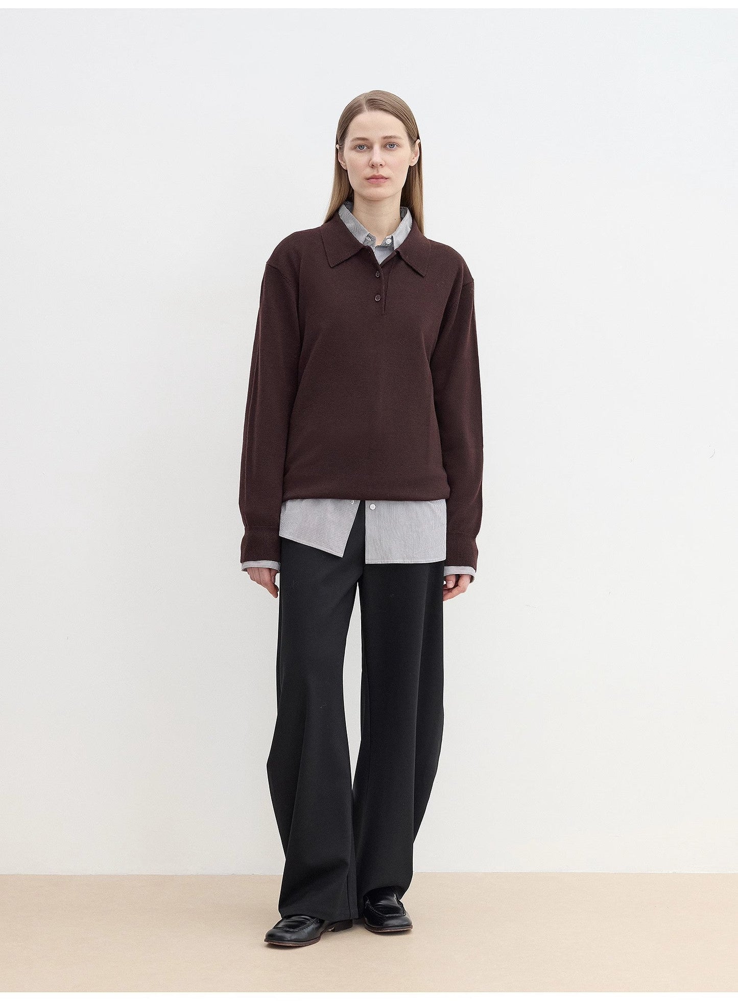Person wearing a cozy brown sweater over a light shirt with sharp black pants against a white background. This classic lesbian outfit is a perfect example of confident lesbian fashion and authentic lesbian style.