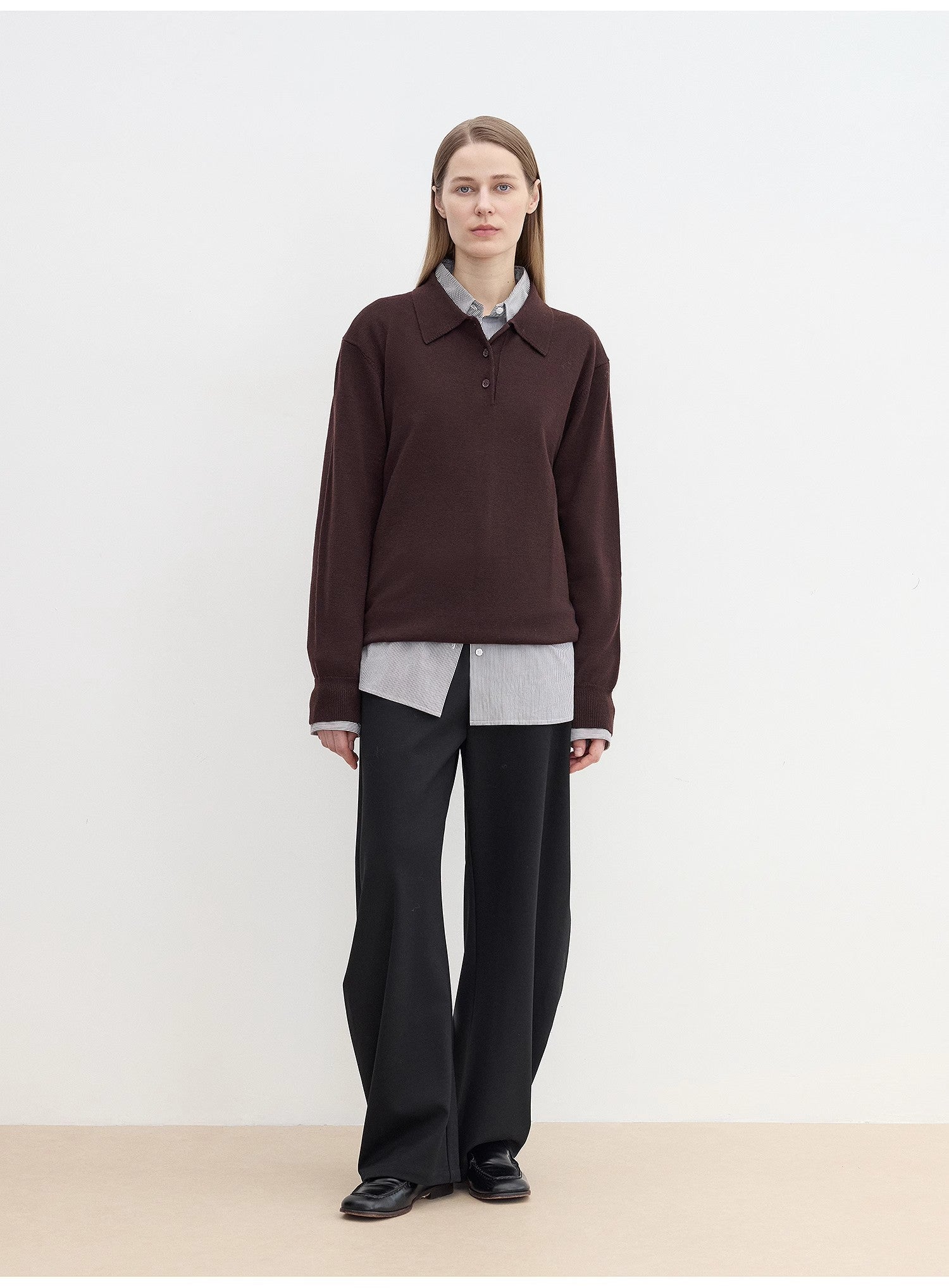 Person wearing a cozy brown sweater over a light shirt with sharp black pants against a white background. This classic lesbian outfit is a perfect example of confident lesbian fashion and authentic lesbian style.