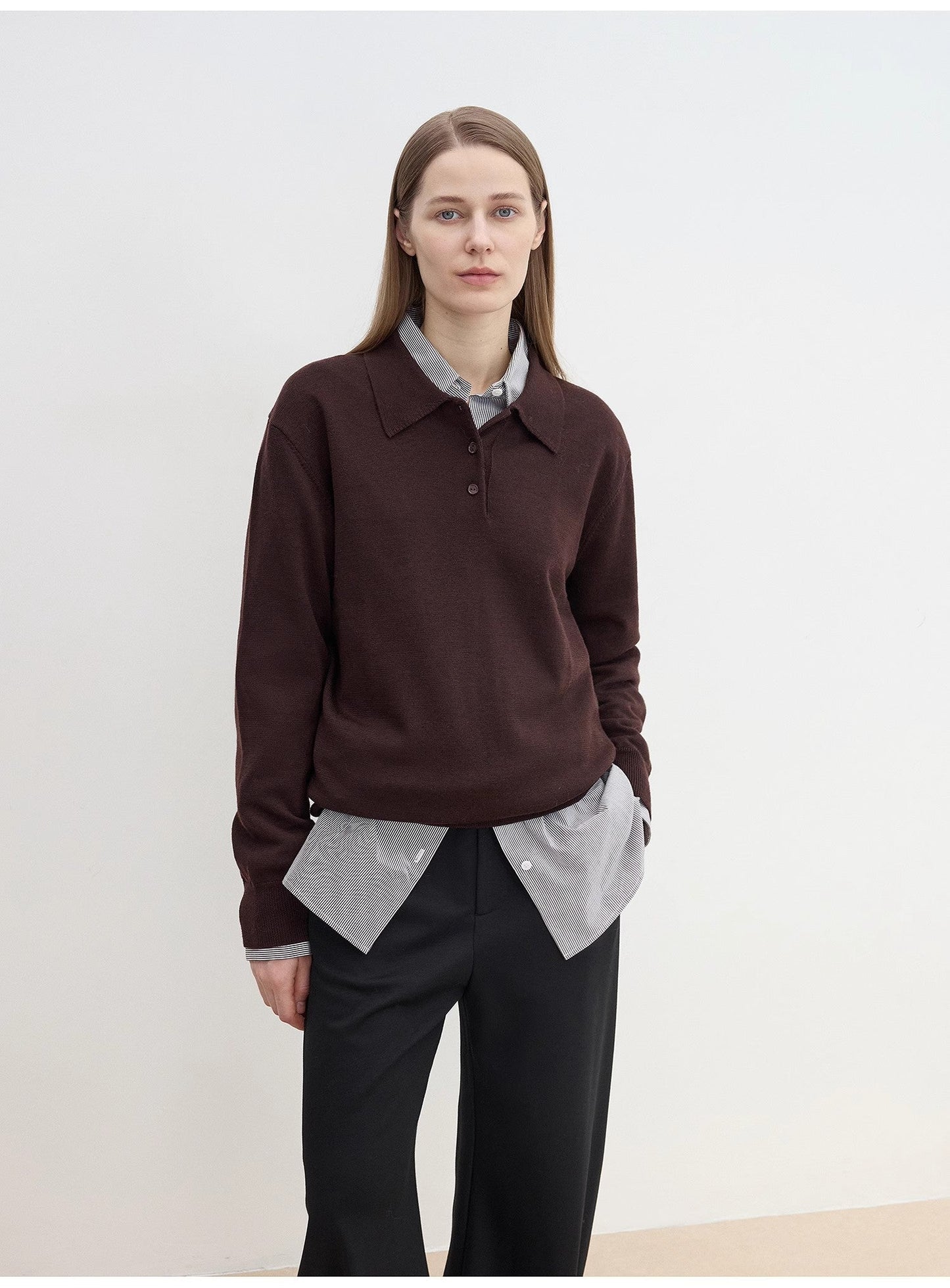 Person wearing a cozy brown sweater over a light shirt with sharp black pants against a white background. This classic lesbian outfit is a perfect example of confident lesbian fashion and authentic lesbian style.