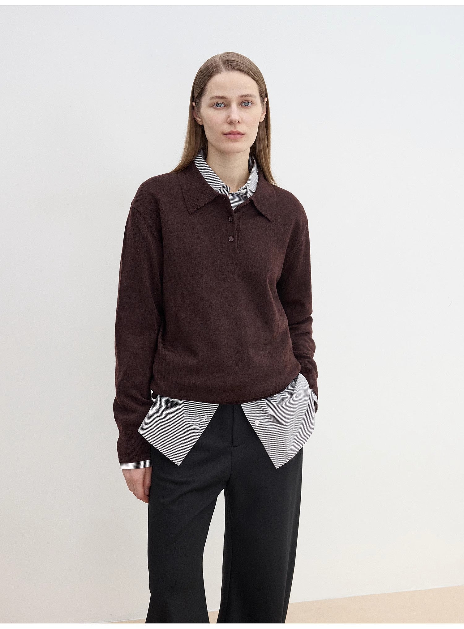 Person wearing a cozy brown sweater over a light shirt with sharp black pants against a white background. This classic lesbian outfit is a perfect example of confident lesbian fashion and authentic lesbian style.