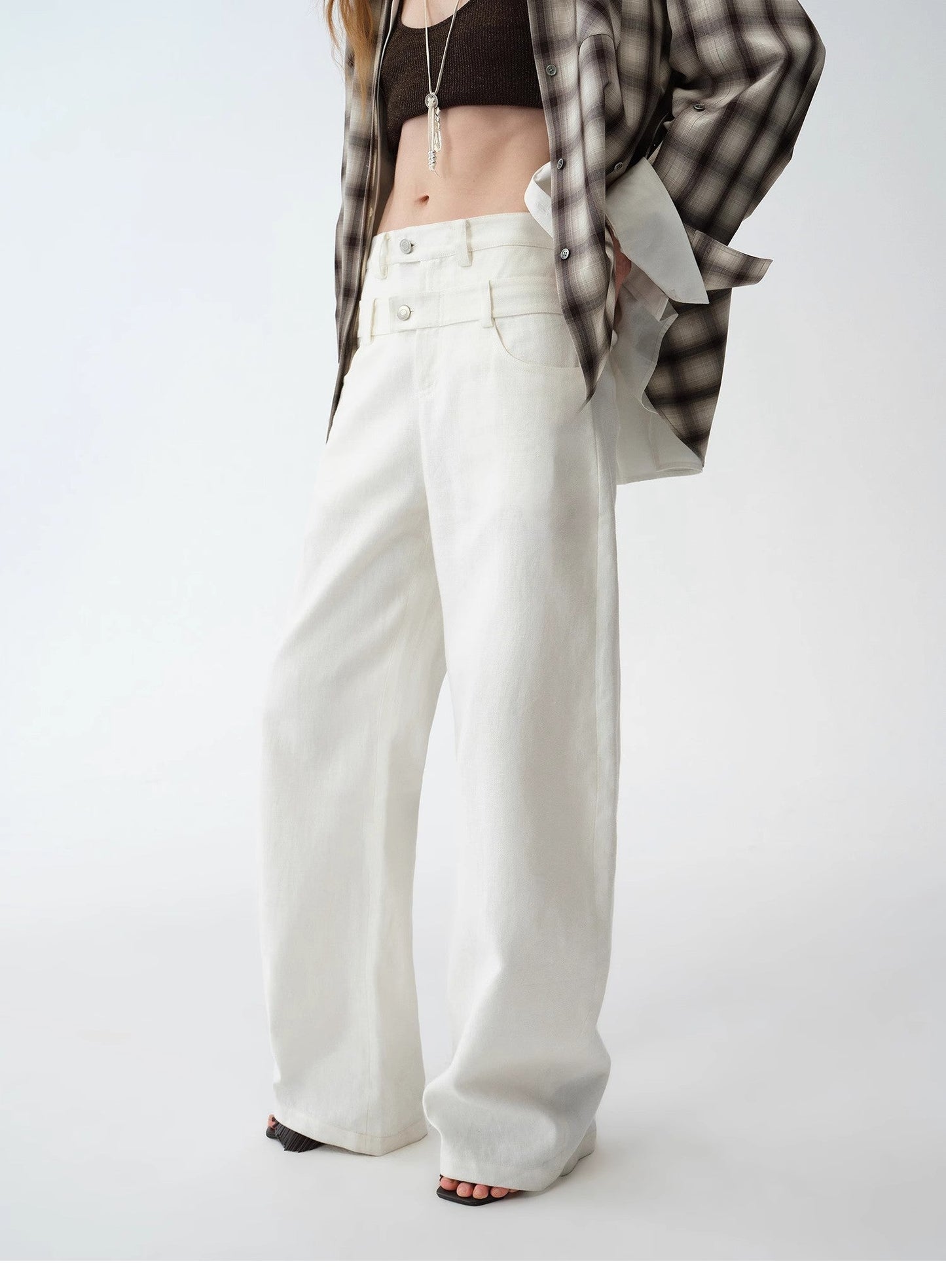 Person wearing white wide-leg pants with a plaid shirt on a white background. This casual lesbian outfit is a perfect example of confident lesbian fashion style and effortless lesbian style.