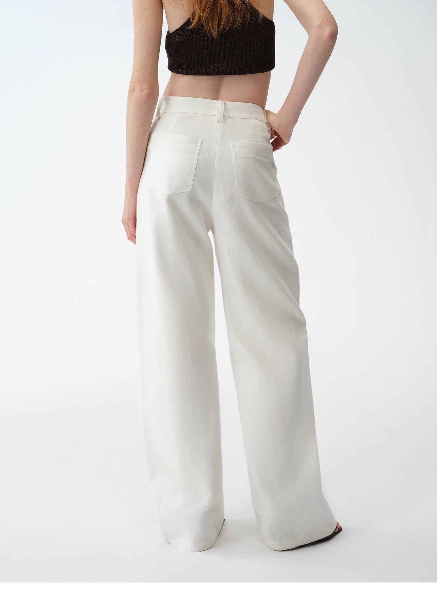 Person wearing white wide-leg pants and a black top on a white background. This casual lesbian outfit is a perfect example of confident lesbian fashion style and effortless lesbian style.