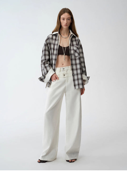 Person wearing an unbuttoned plaid shirt over a black bralette with white pants. This casual lesbian outfit is a perfect example of confident lesbian fashion style and effortless lesbian style.