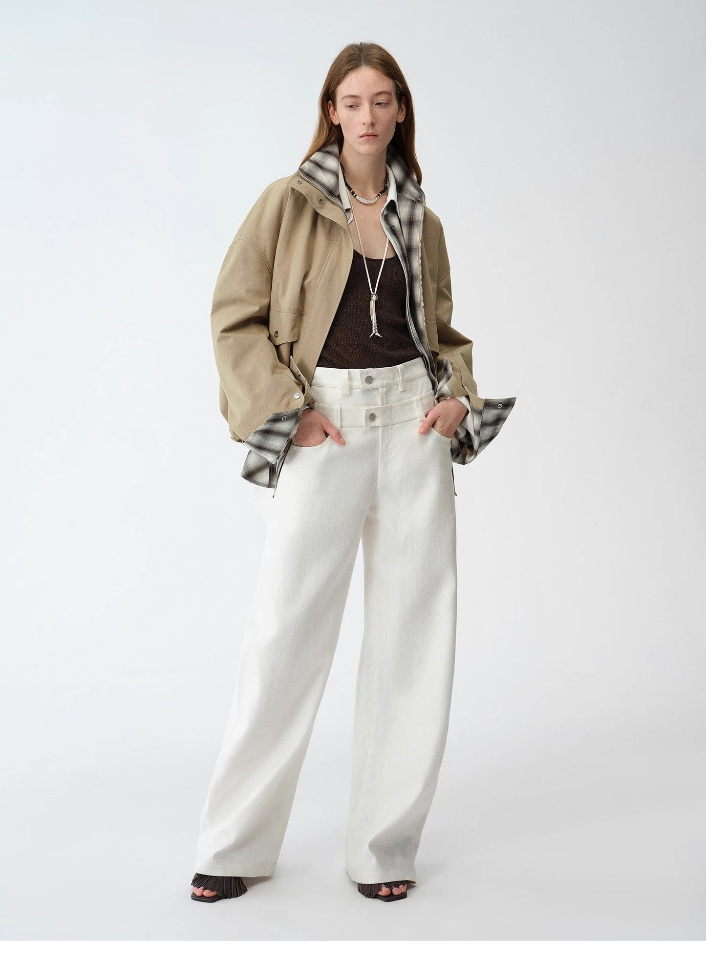 Person wearing a beige jacket, plaid shirt, brown top, white pants, and black shoes on a white background. This casual lesbian outfit is a perfect example of confident lesbian fashion style and effortless lesbian style.