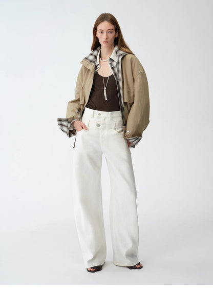 Person wearing a brown jacket, white pants, and a patterned scarf on a white background. This casual lesbian outfit is a perfect example of confident lesbian fashion style and effortless lesbian style.