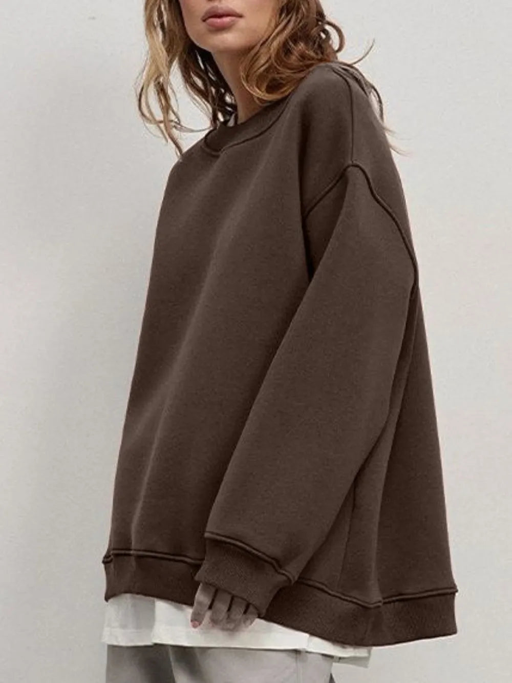 Person wearing a comfortable brown oversized sweatshirt on a plain background. This classic lesbian outfit is a perfect example of casual lesbian clothing and relaxed lesbian style