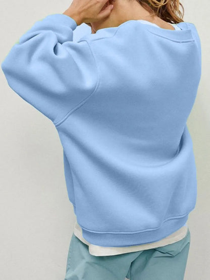 Person wearing a comfortable light blue sweatshirt and matching pants set against a neutral background. This relaxed lesbian outfit is a perfect example of casual lesbian clothing and soft lesbian style.