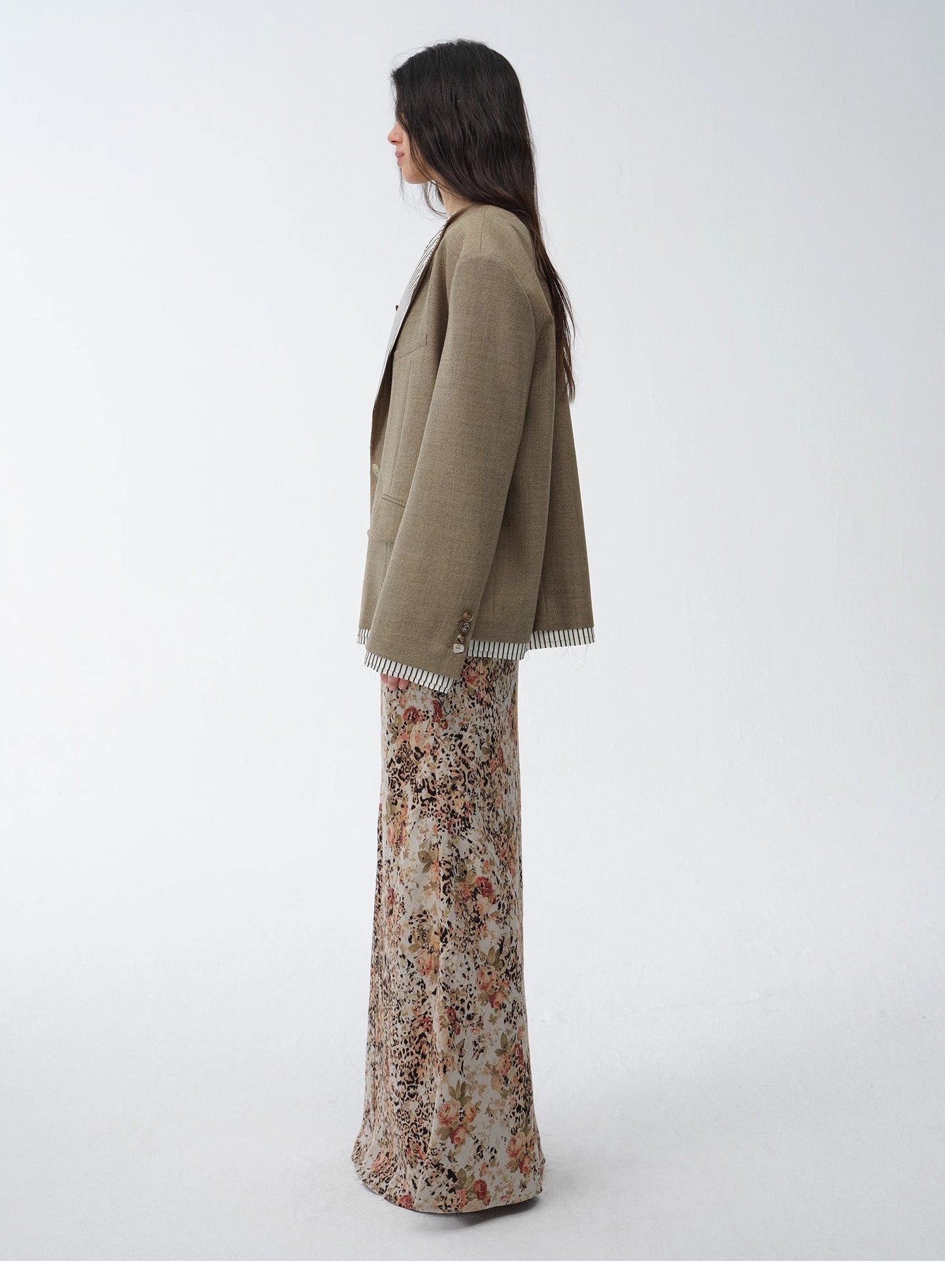 Woman wearing a soft green cardigan over vibrant floral pants on a white background. This comfortable lesbian outfit is a strong example of cozy lesbian fashion and playful lesbian style.