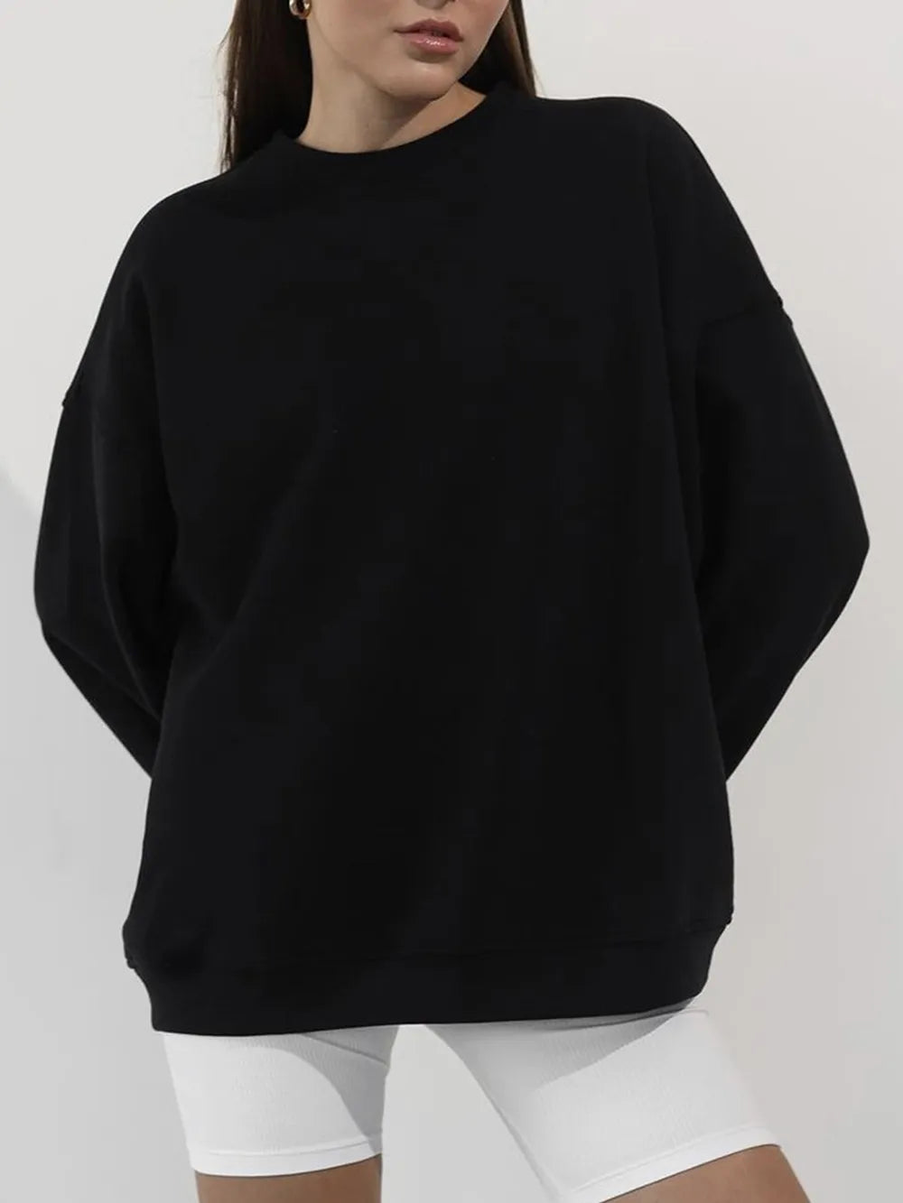 Person wearing a comfortable black oversized sweatshirt with a crisp white shirt underneath on a plain background. This classic lesbian outfit is a perfect example of casual lesbian fashion and authentic lesbian style.