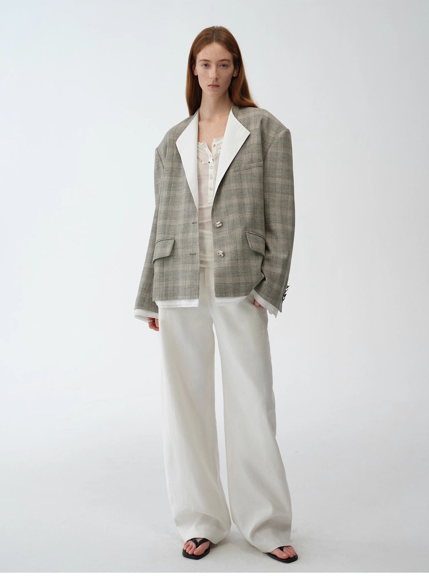 Woman wearing a checkered blazer and white pants on a white background