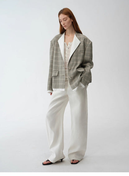 Woman wearing a gray plaid blazer and white pants on a white background