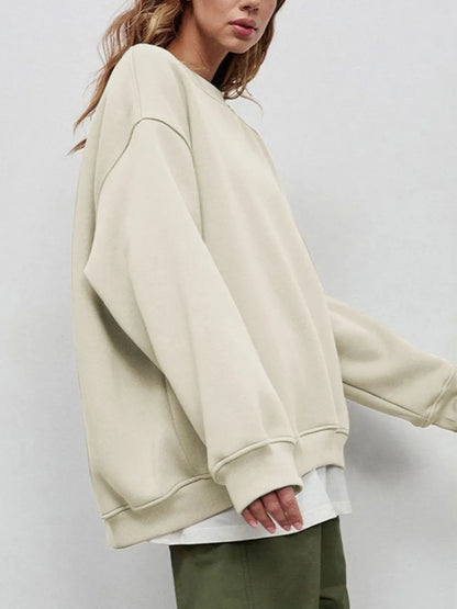 Person wearing a comfortable white sweatshirt, sitting on a step against a gray wall. This classic lesbian outfit is a perfect example of casual lesbian clothing and relaxed lesbian style.