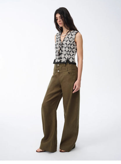 Woman wearing a patterned top and olive green wide-leg pants on a white background. This casual lesbian outfit is a perfect example of confident lesbian fashion style and effortless lesbian style.