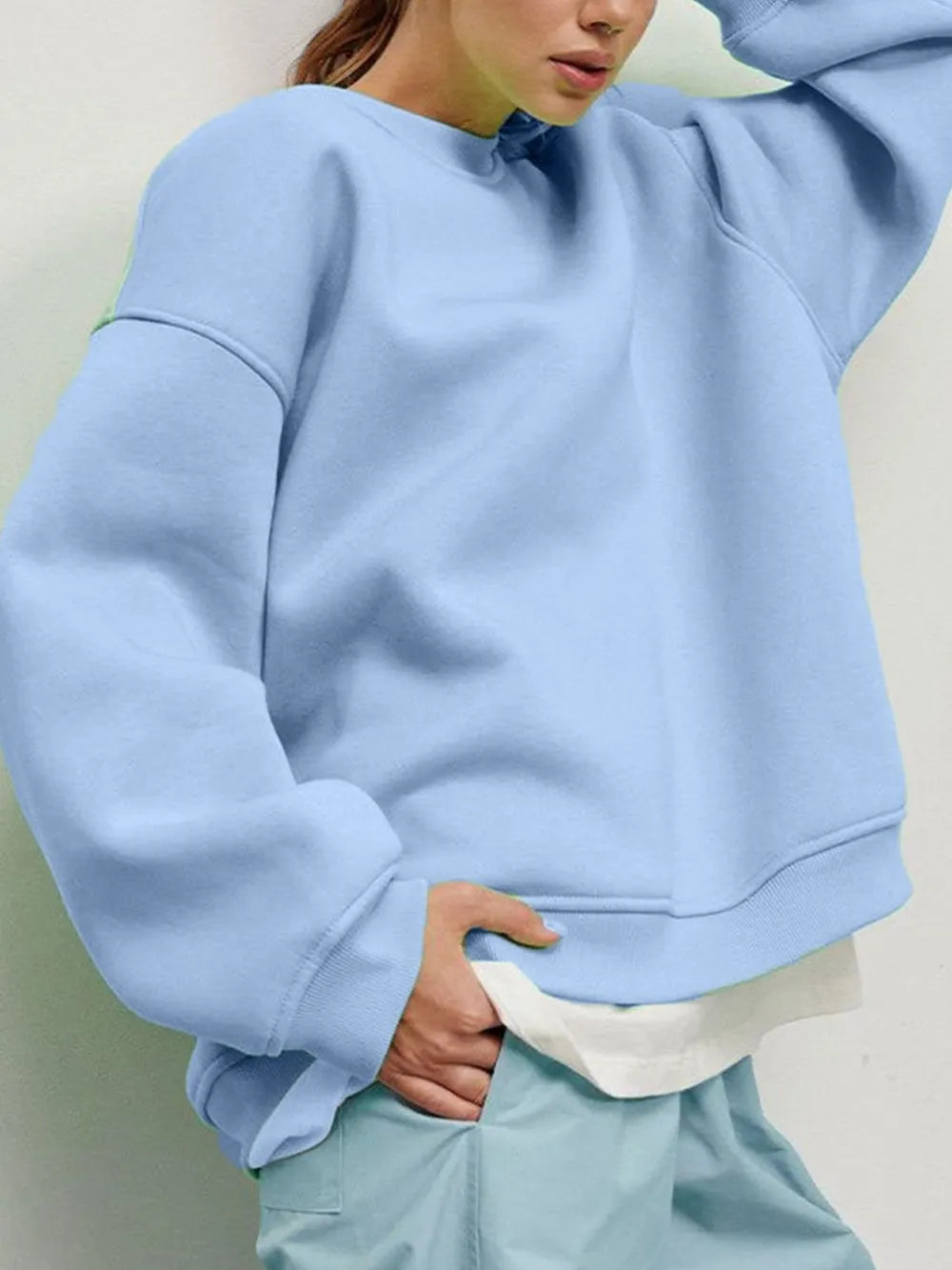 Person wearing a comfortable light blue sweatshirt and matching pants set against a neutral background. This relaxed lesbian outfit is a perfect example of casual lesbian clothing and soft lesbian style.