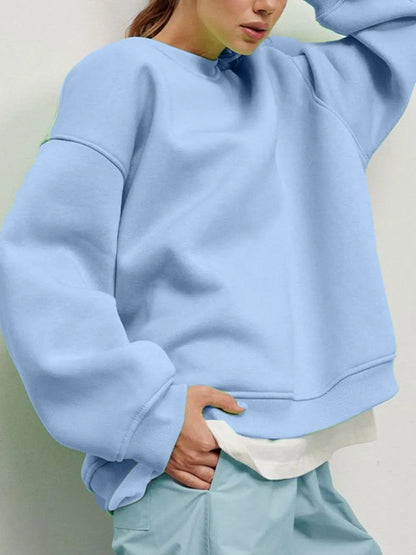 Person wearing a comfortable light blue sweatshirt and matching pants set against a neutral background. This relaxed lesbian outfit is a perfect example of casual lesbian clothing and soft lesbian style.
