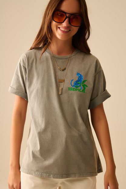 Woman wearing a gray t-shirt with a blue and green graphic design on a beige background
