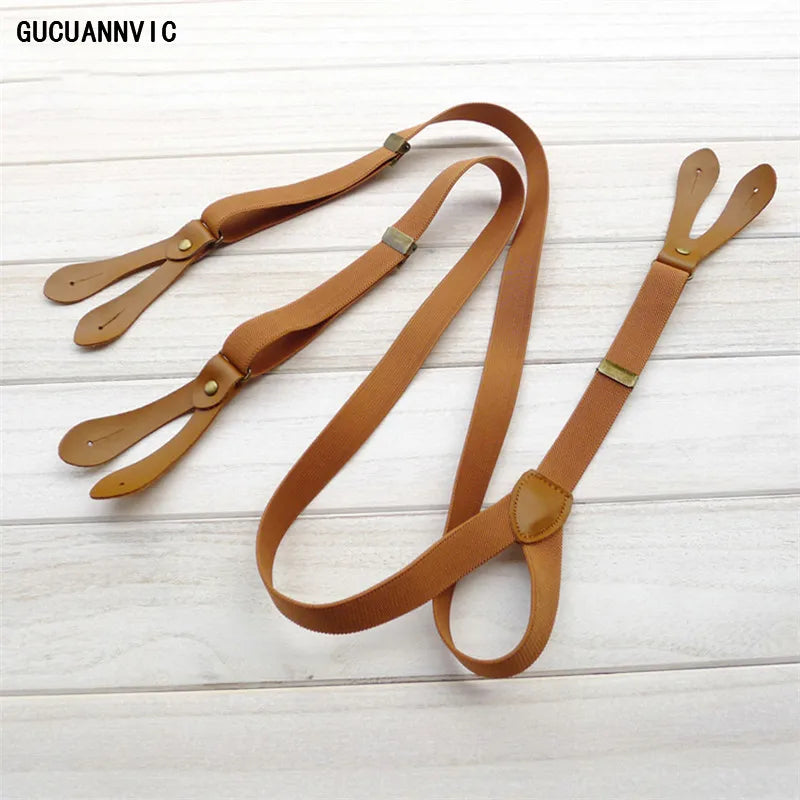 Close-up of brown leather suspenders featuring 'GUCUANNY I C' branding, laid on a light wooden surface. These classic accessories are essential for a sharp lesbian outfit and defining an authentic lesbian style.