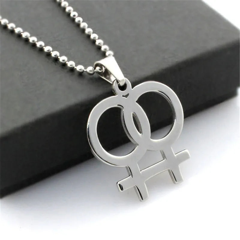 Silver necklace featuring a double gender symbol pendant on a dark surface. A key piece of lesbian fashion to define your lesbian style. Essential lesbian attire accessory for a confident lesbian outfit.