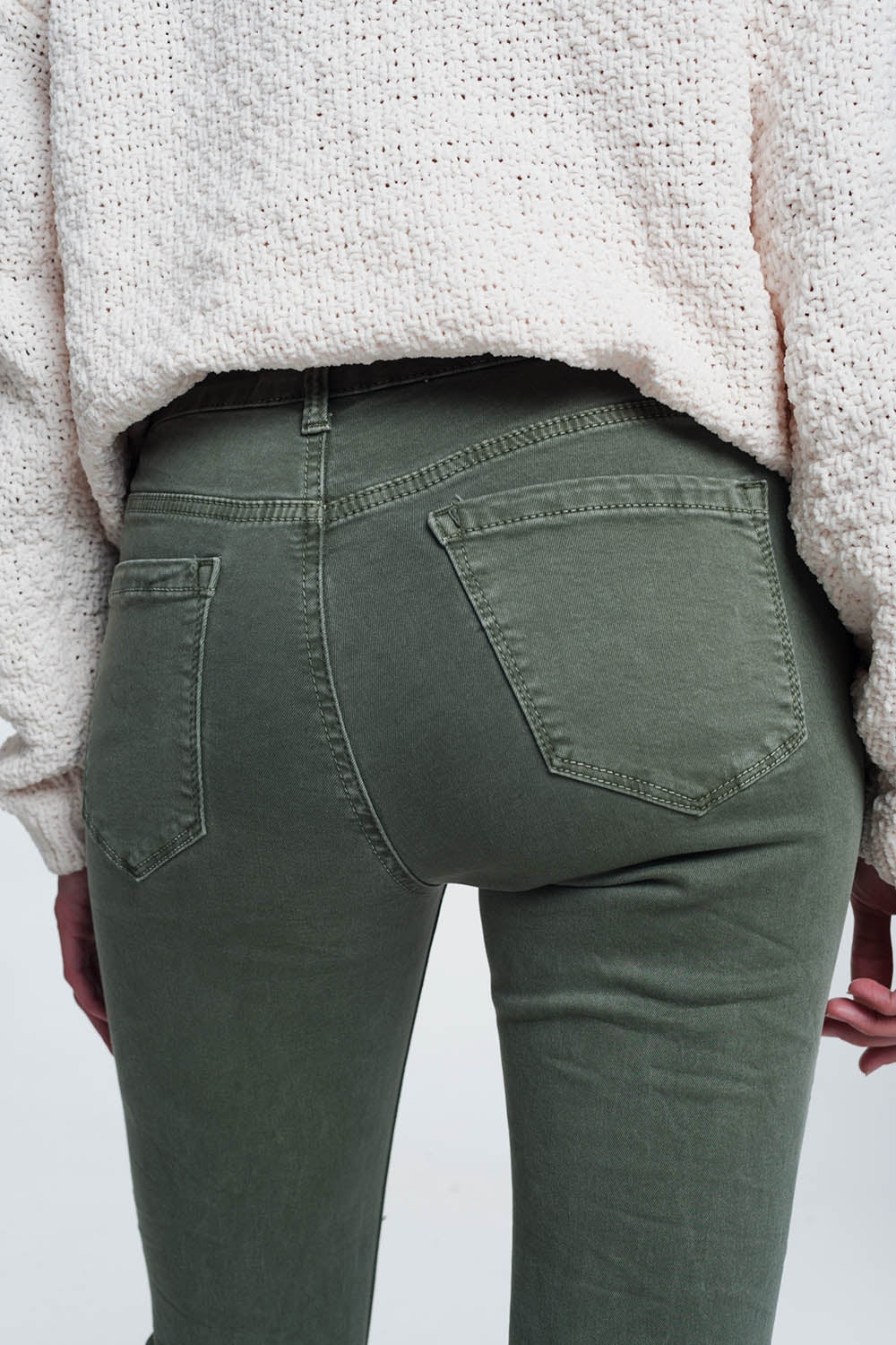 Person modeling green pants on a plain background. These comfortable lesbian clothing trousers are a staple of confident, everyday lesbian style and a sharp lesbian outfit.