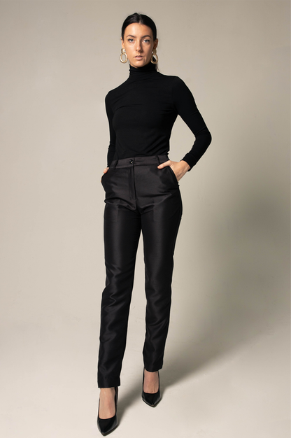 Woman wearing a classic black turtleneck and matching black pants against a neutral background. This minimalist lesbian outfit is a perfect example of confident lesbian fashion and sophisticated lesbian style.