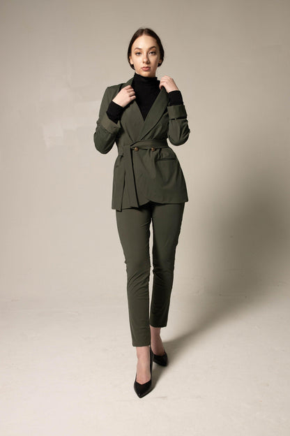 Woman wearing a tailored green suit on a plain background. This sharp, professional lesbian outfit is a perfect example of formal lesbian fashion and sophisticated lesbian style.