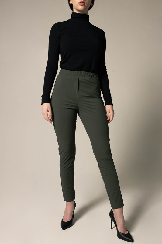 Person wearing a black turtleneck and loose green pants against a beige background. This stylish lesbian outfit is a sharp example of lesbian fashion style and confident lesbian attire.