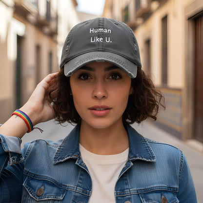 Woman wearing a cap with 'Human Like U.' text and casual attire on a city street. This confident headwear is a perfect accessory for defining authentic lesbian style and completing a relaxed lesbian outfit.