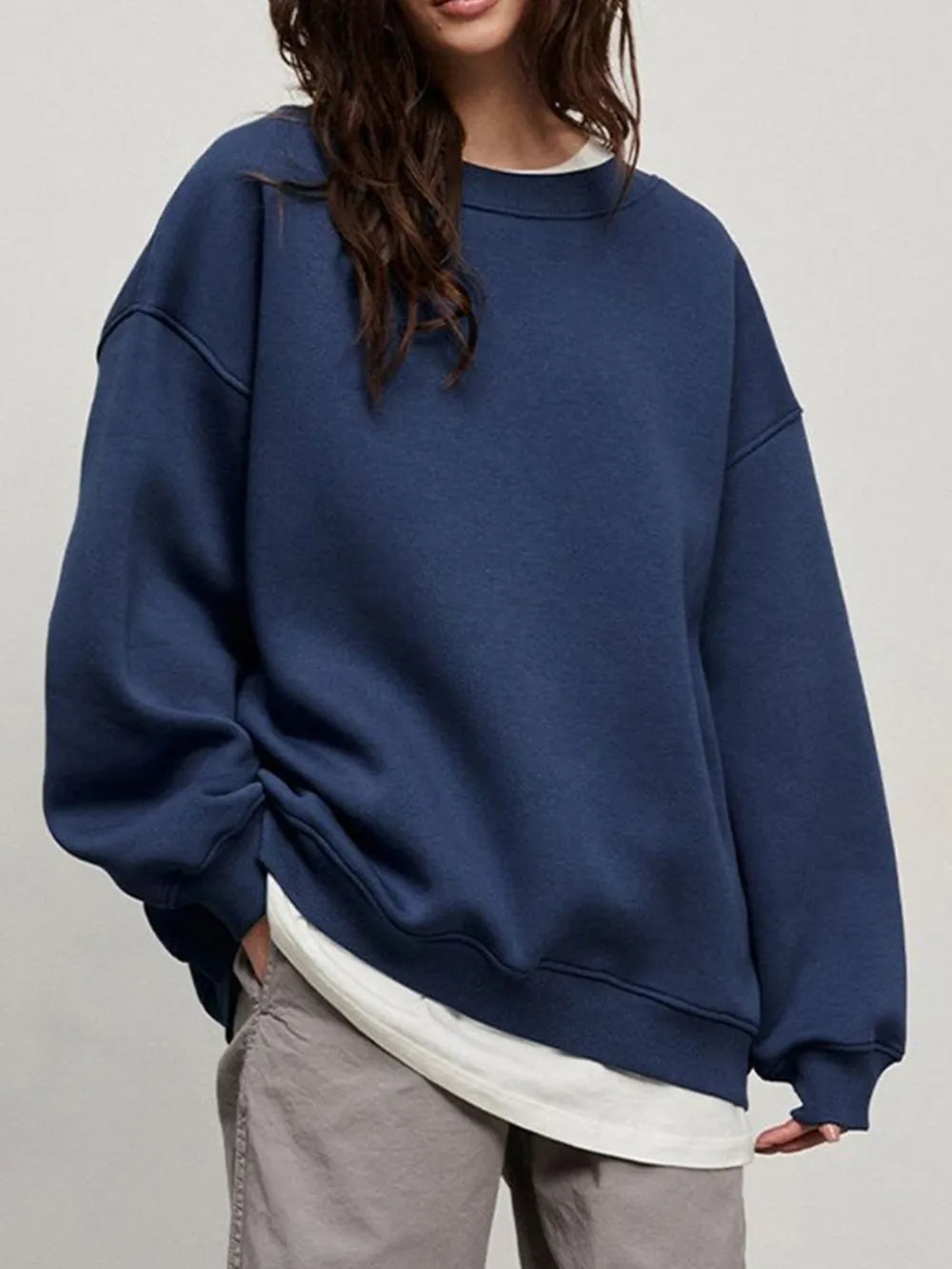 Person wearing a comfortable blue oversized sweatshirt on a plain background. This classic lesbian outfit is a perfect example of casual lesbian clothing and relaxed lesbian style.