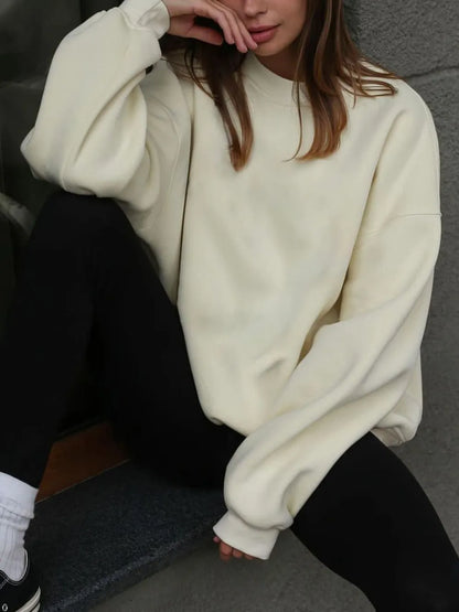 Person wearing a comfortable white sweatshirt, sitting on a step against a gray wall. This classic lesbian outfit is a perfect example of casual lesbian clothing and relaxed lesbian style.