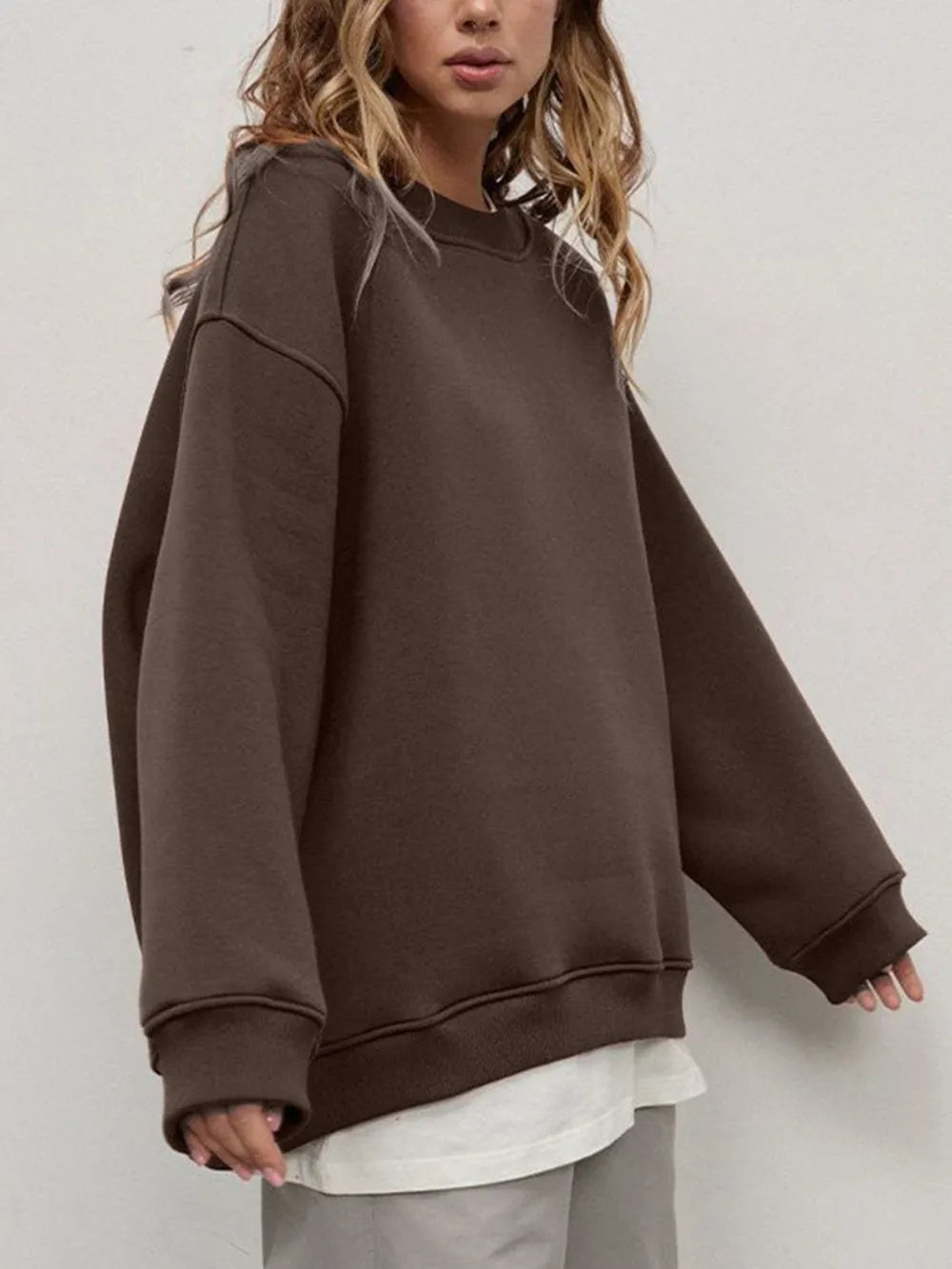 Person wearing a comfortable brown oversized sweatshirt on a plain background. This classic lesbian outfit is a perfect example of casual lesbian clothing and relaxed lesbian style