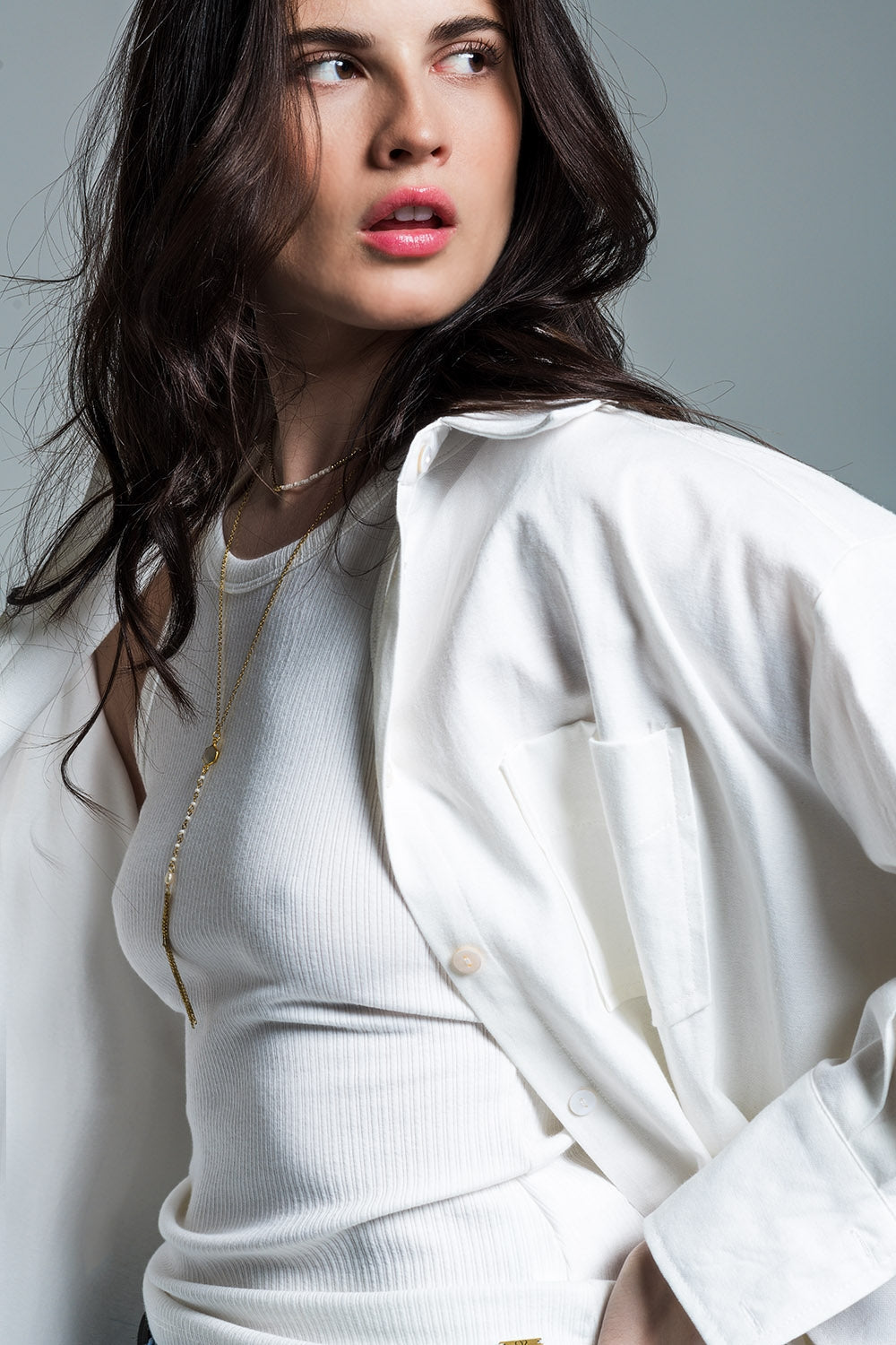 Woman modeling a clean, confident white outfit (blouse and pants) on a plain background. This monochrome lesbian outfit is a perfect example of minimalist lesbian fashion and authentic lesbian style.