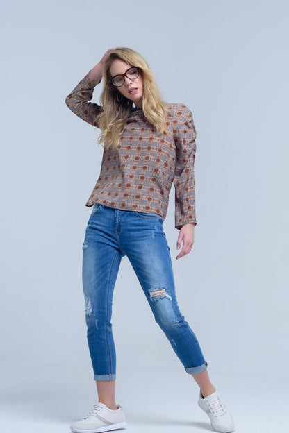 Woman wearing a patterned shirt, blue jeans, and white sneakers against a light gray background. This comfortable lesbian outfit is a perfect example of casual lesbian fashion and authentic lesbian style.