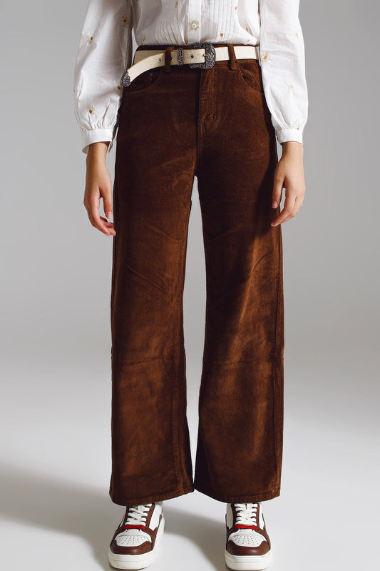 Person models lesbian fashion wearing comfortable brown corduroy pants against a plain background. This relaxed lesbian outfit is a perfect example of casual lesbian style.