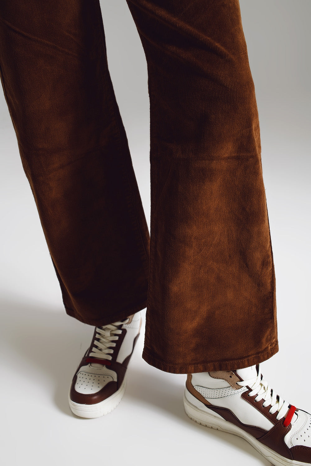 Brown suede pants worn with white and brown sneakers against a light gray background. This comfortable and confident lesbian outfit is a perfect example of casual lesbian style and essential lesbian fashion.