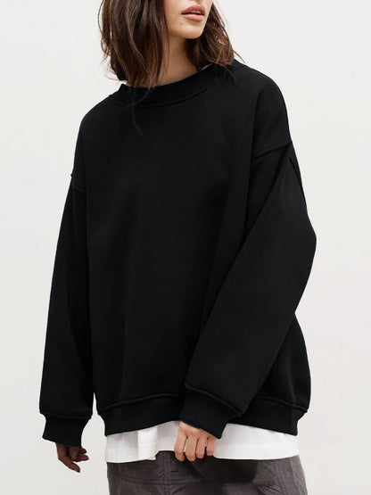 Person wearing a comfortable black oversized sweatshirt with a crisp white shirt underneath on a plain background. This classic lesbian outfit is a perfect example of casual lesbian fashion and authentic lesbian style.
