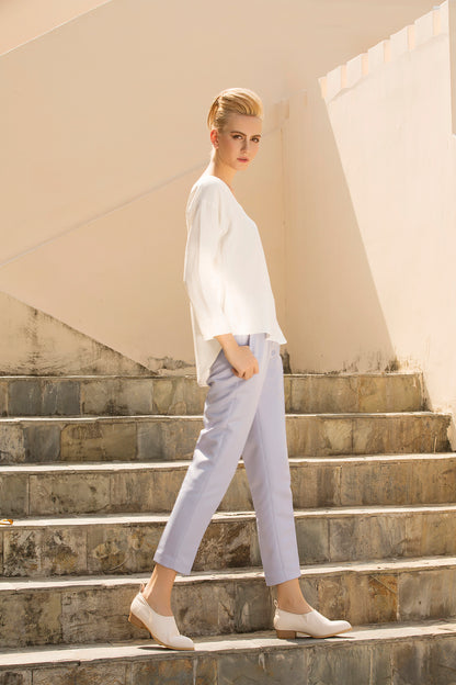 Woman wearing a white top and light gray pants while walking up stone steps. This confident lesbian outfit is a perfect example of casual lesbian fashion and authentic lesbian style.