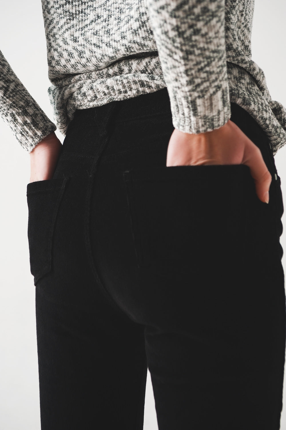Person wearing sharp black pants against a plain background. This confident wardrobe staple is an essential piece of lesbian clothing and foundational to authentic lesbian style.