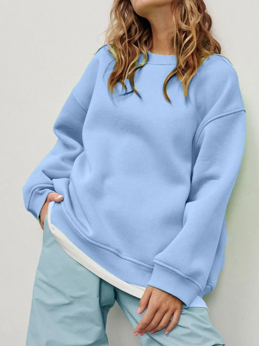 Person wearing a comfortable light blue sweatshirt and matching pants set against a neutral background. This relaxed lesbian outfit is a perfect example of casual lesbian clothing and soft lesbian style.