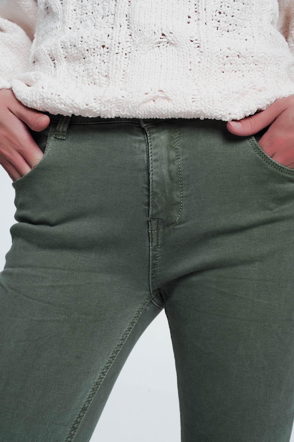 Close-up of green pants worn by a person on a light gray background. These comfortable lesbian clothing trousers define a confident, everyday lesbian style and can be part of any sharp lesbian outfit.