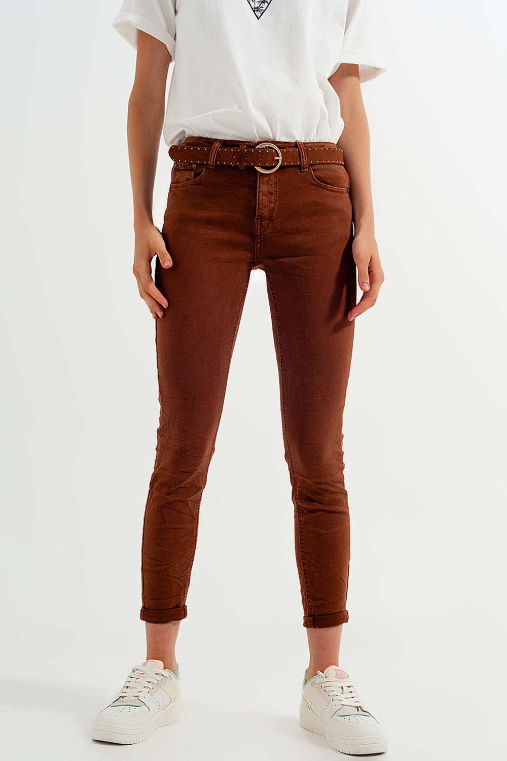 Person wearing classic brown jeans and a white shirt on a white background. This clean and confident lesbian outfit is a perfect example of casual lesbian fashion and authentic lesbian style.